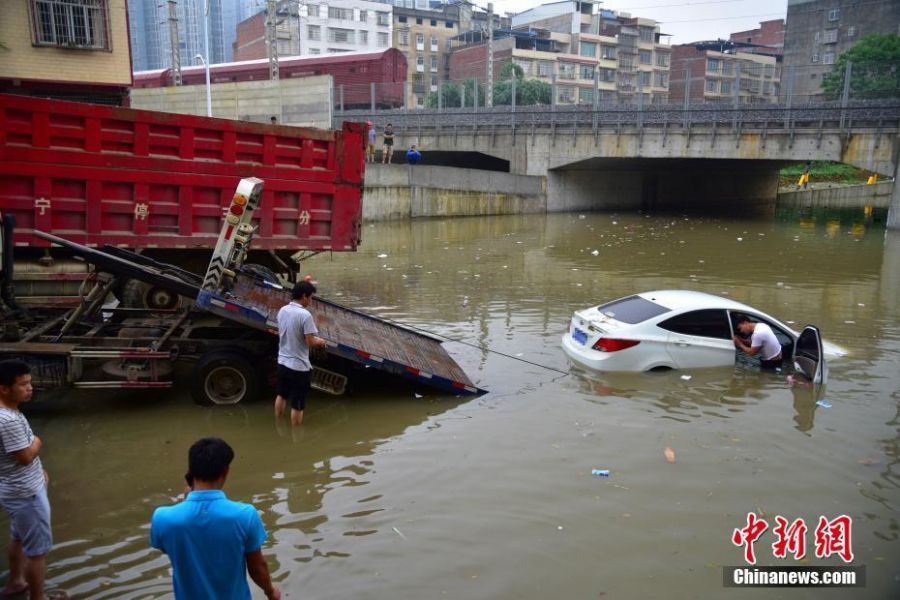 6月13日早上6时许，广西柳州市下起倾盆大雨，致使该市柳江区拉堡镇乐都大道涵洞积水约2米，多辆停放在此的车辆被水泡。该涵洞还未启用，附近不少居民将此处当停车场，而入口处被绿色的铁丝网围住，悬挂着“施工重地，闲人免进”，“施工通道，禁止停车”等字样的警示牌。图为道路救援工作人员正将车辆移出水中。 王以照 摄