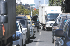 一名妇女利用车辆等红灯的机会，向车主派发广告卡片 都市时报首席记者 张玉杰